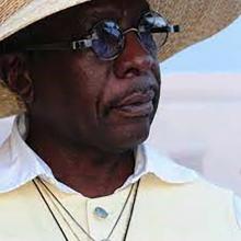 michael engs headshot, african american man, wearing eyeglasses and straw hat under a sunny sky