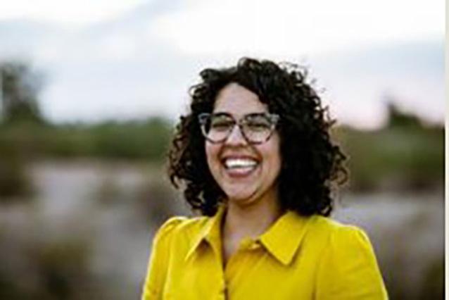 Anita Huizar-Hernandez, female, dark curly hair, wearing eye glasses and yellow blouse