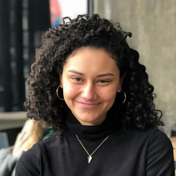 young female, dark curly hair, wearing a black blouse